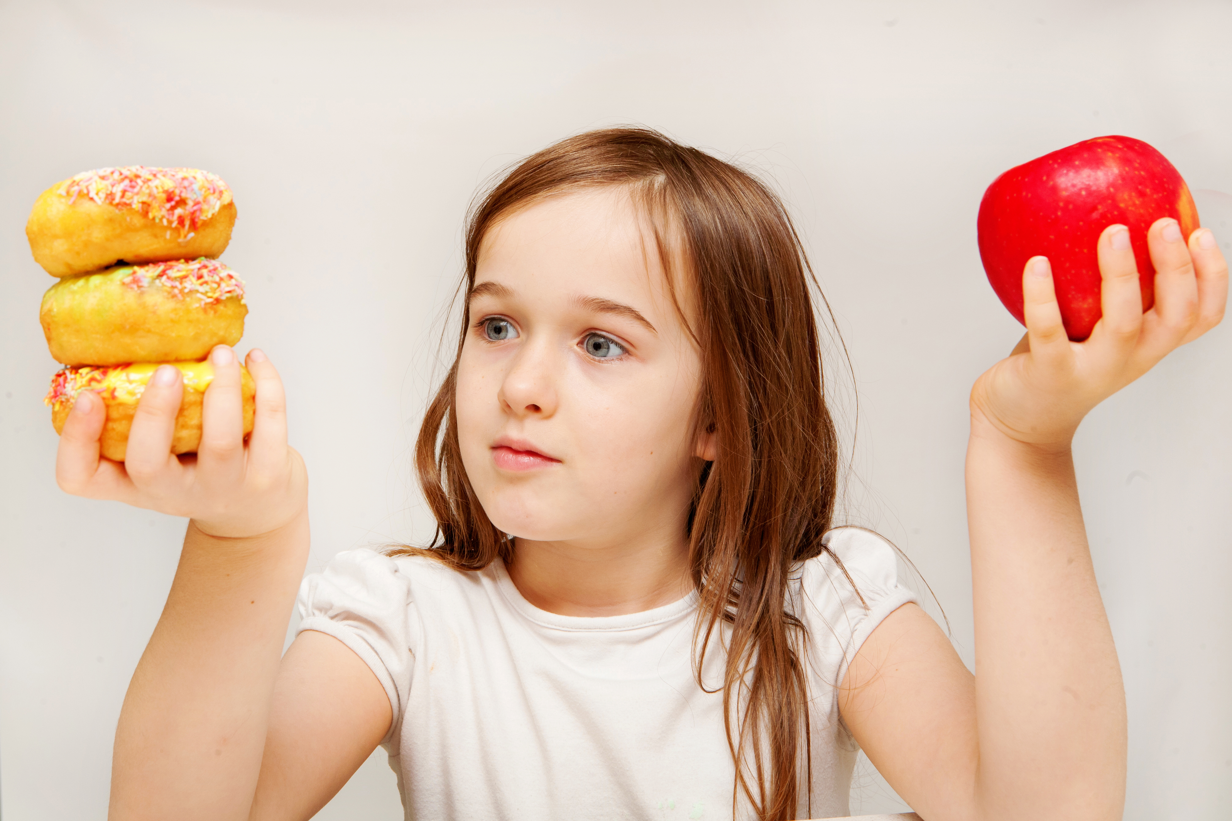 This photo depicts a young girl making decisions betwen healthy y food and unhealthy food.